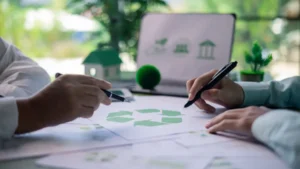 Deux personnes analysent des documents avec le symbole recyclage, décor vert et écran en fond.